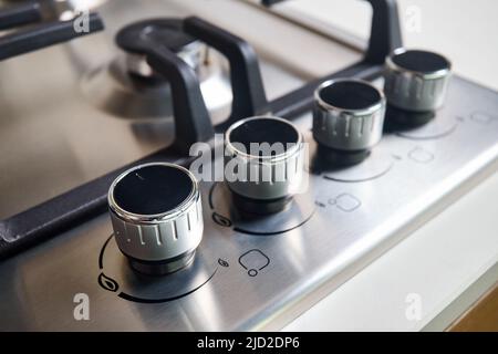 Hob cooker oven grill stainless steel control knobs selective focus over out of focus oven with burner background. Stock Photo
