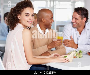 Networking over a sandwich.... A pretty young woman enjoying lunch with her colleagues. Stock Photo