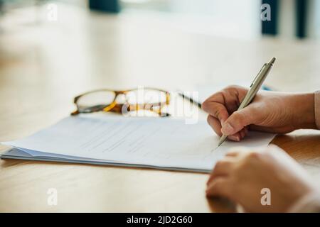 Sign on the dotted line. Closeup shot of an unidentifiable businesswoman filling in paperwork in an office. Stock Photo