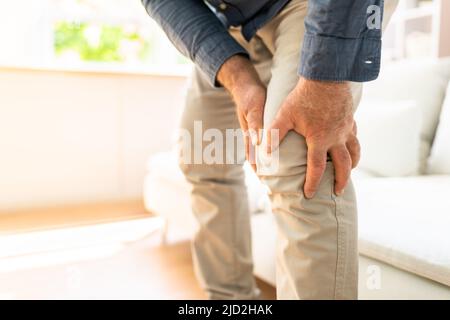 Man Suffering From Knee Pain While Trying To Stand up Stock Photo