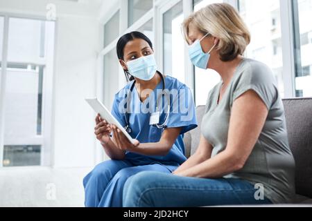 Personal treatment plans tailored to every patient. Shot of a young doctor using a digital tablet during a consultation with a senior woman. Stock Photo