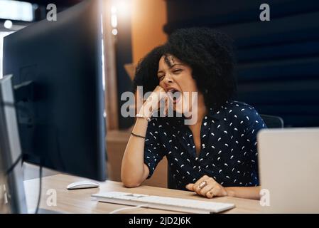 This work has made me so tired. Shot of a young tired looking female designer falling asleep behind her computer at the office during the day. Stock Photo