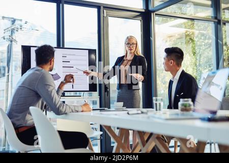 Making every minute of the meeting count. Shot of a young businesswoman delivering a presentation to her colleagues in the boardroom of a modern Stock Photo