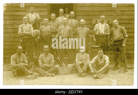 Original WW1 era postcard of soldiers on cleaning duties outside a hut, brushes, mop, shovel, tin bath, fire bucket, man has army canteen on belt. Possibly fire crew. at their army barracks .U.K. Stock Photo