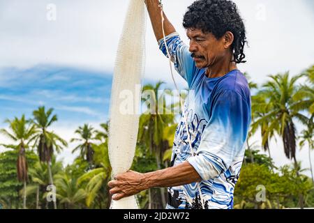 Fisherman holding his net with palm trees in the background. Stock Photo