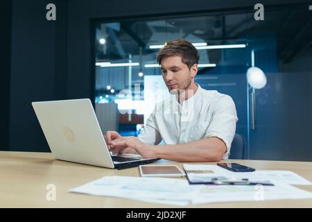 Serious young businessman working in the office on a laptop Stock Photo