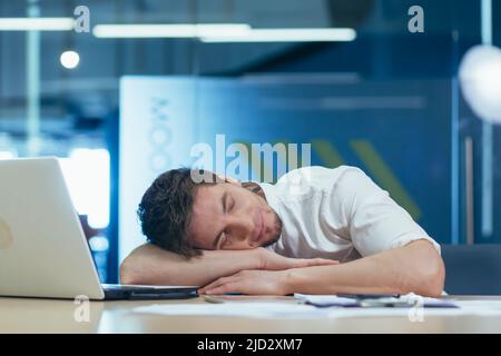 Young tired businessman sleeping on the desk at workplace in the office Stock Photo