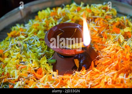 Flame in an oil lamp amidst a bowl of flowers, welcoming ceremony in an Indian ashram Stock Photo