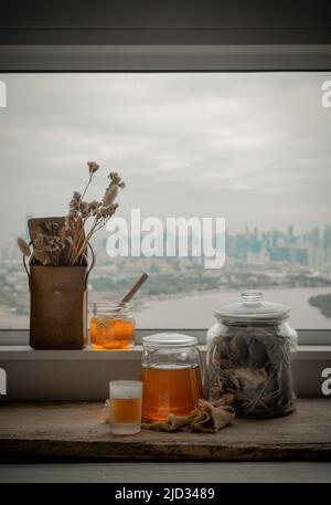 Refreshing with Chinese herbal tea (Jub Lieng) served with honey on old wooden table with city view. Herbal plant and healthy drinks concept, Selectiv Stock Photo