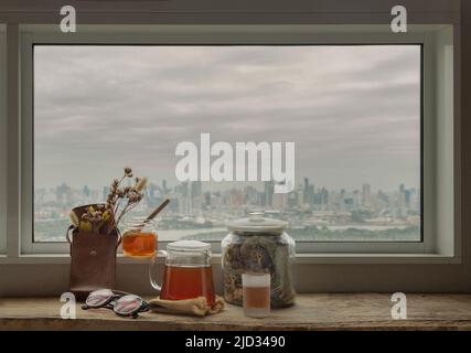 Refreshing with Chinese herbal tea (Jub Lieng) served with honey on old wooden table with city view. Herbal plant and healthy drinks concept, Selectiv Stock Photo