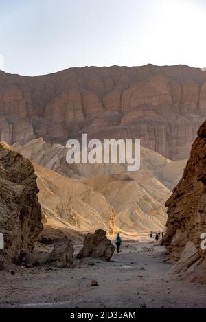 Hikers at the badlands at Golden Canyon in Death Valley National Park ...