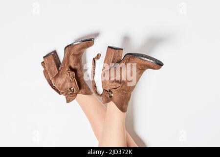 Womans legs in autumn beige leather suede boots Stylish women's shoes made from natural materials on white background Stock Photo