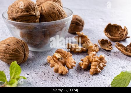 Selective focus on walnuts in a bowl and kernels on white background Stock Photo