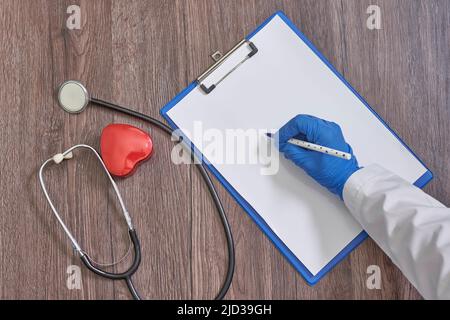 Phonoscop pen and notebook for recording the results of a patient examination on the table. Doctor writing Stock Photo
