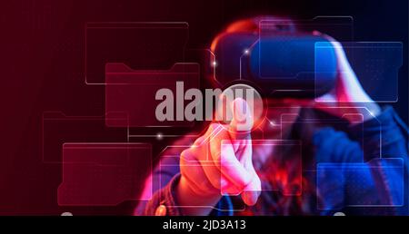 Portrait of young woman in blue and red lighting wearing virtual reality glasses pressing a button connected to different screens in cyberspace Stock Photo