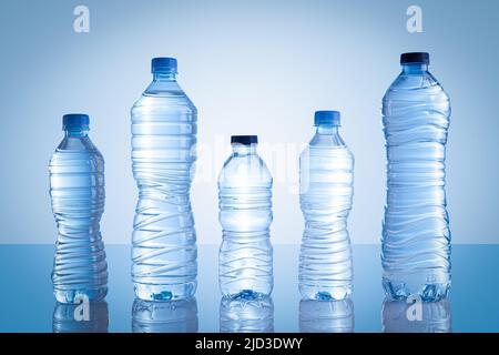 Collection of different plastic water bottles isolated on blue background. Stock Photo