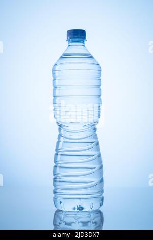 Transparent plastic bottle with mineral water isolated on blue background. Vertical format. Stock Photo