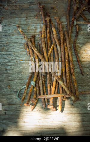 A lot of old rusty bent nails lying on a wooden board. Stock Photo