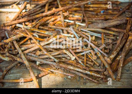 A lot of old rusty bent nails lying on a wooden board. Stock Photo