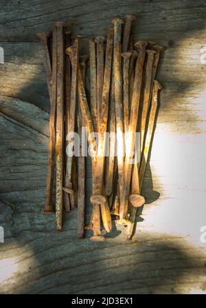 A lot of old rusty bent nails lying on a wooden board. Stock Photo