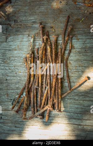 A lot of old rusty bent nails lying on a wooden board. Stock Photo