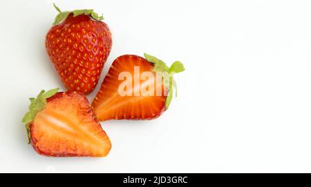 Juicy strawberries and two halves. Strawberries isolated on a white background. Place for text. Stock Photo