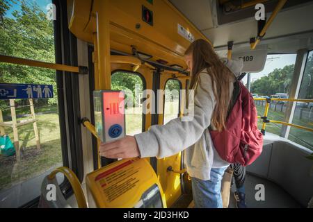 A young woman is seen pressing the stop button in a public transportation tram in Warsaw, Poland on 14 June, 2022. Stock Photo