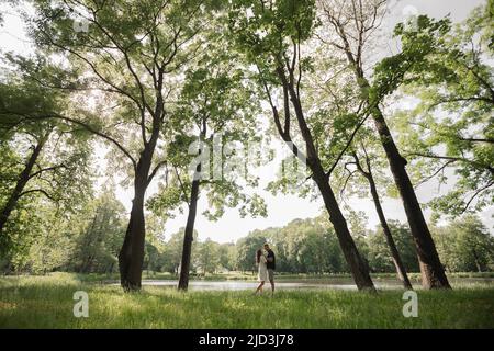 full length of happy young couple in summer standing near lake, embracing, happy people in park Stock Photo