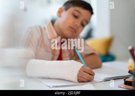 Back to school. Thinking child boy writing, drawing in notebook sitting at desk and doing homework. High quality photo Stock Photo