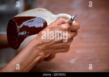 Close up view of an elderly woman molding a clay block and making a ceramic pot Stock Photo