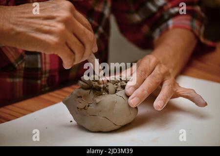 Close up view of an elderly woman molding a clay block  and making ceramic pot Stock Photo