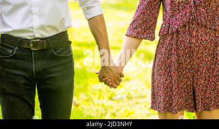 Hold on, hands, couple. Couple holding their hands on sun day. couple holding hand in the park. Couplesholding hand. Young couple in love walking in Stock Photo
