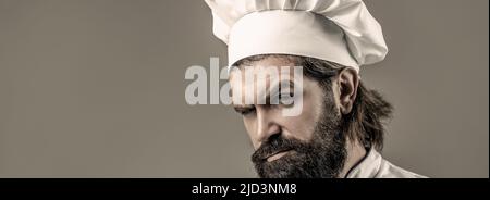Confident bearded male chef in white uniform. Serious cook in white uniform, chef hat. Portrait of a serious chef cook Stock Photo