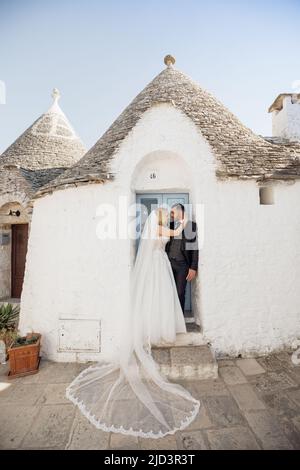 Vertical portrait glad loving romantic married couple, blond woman in white dress and black-haired man in tuxedo, Italy Stock Photo