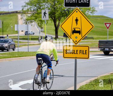 Road sign telling cyclists and car drivers that they most form single file as the approach roundabout Stock Photo