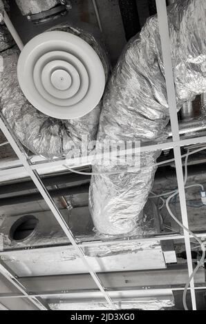 Ventilation system with pipes in silver insulation material in suspended ceiling during renovation. Stock Photo