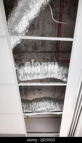 Ventilation pipes in silver insulation material in suspended ceiling during renovation. Stock Photo