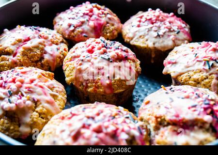 Sweet homemade muffins covered with icing and sprinkling .Close-up photo.  Stock Photo