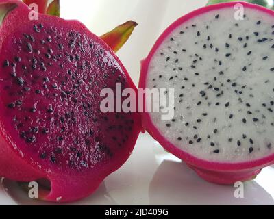 Asian tropical exotic fruit pitahaya cactus red and white, cut in half. Pulp and seeds outside, front view. Stock Photo
