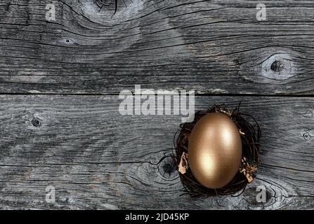 Golden egg in nest on rustic wood background for investment or retirement concept Stock Photo
