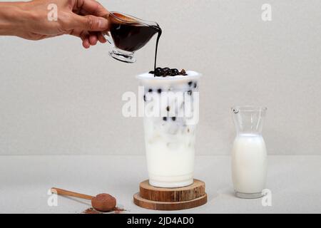 Pour Palm Sugar Liquid on Boba Milk Tea with in a Tall Glass with Ice on Grey Stone Table Stock Photo