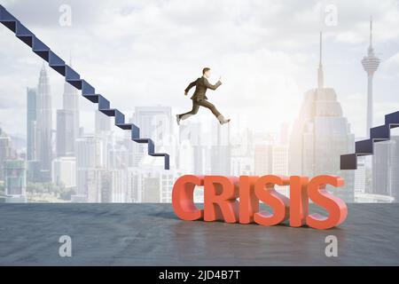 Financial crisis and risk management concept with businessman in black suit jumping from stairs between gap with crisis word to new stairs at city bac Stock Photo