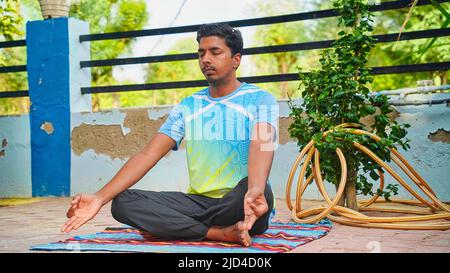 Attractive young Indian man sitting in yoga pose at home. Practicing yoga in the every morning. Stock Photo