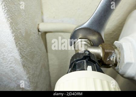 Stuttgart, Germany - February 01, 2022: Replace old Danfoss radiator thermostat valve. Open-end wrench removes component from the heater. Modernizatio Stock Photo