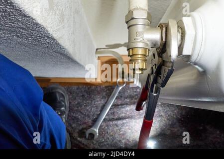 Stuttgart, Germany - February 01, 2022: Replace old danfoss radiator thermostat valve. Pliers removes component from the heater. Modernization of heat Stock Photo