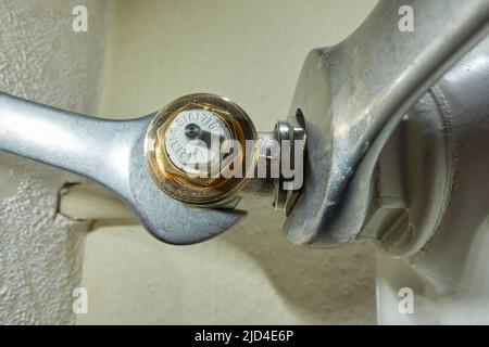 Stuttgart, Germany - February 01, 2022: Install Heimeier thermostat valve. Open-end wrench screws component to the old radiator. Modernize heating sys Stock Photo