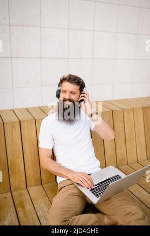 Smiling mid adult man using laptop while sitting on bench Stock Photo