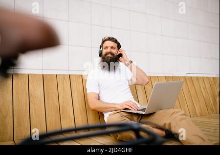 Smiling mid adult man using laptop while sitting on bench Stock Photo
