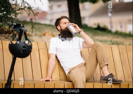 Photo of a man sitting on the bench and drinking coffee Stock Photo