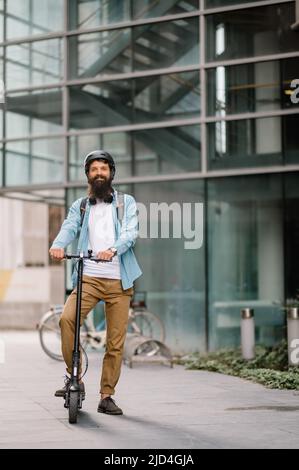 Young business man in a riding an electric scooter on a business meeting, office buildings, scooter, businessman Stock Photo